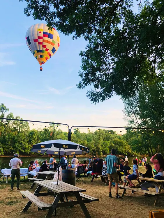 Terrasse du Snack des Pirates en bord de Dordogne avec montgolfière au-dessus