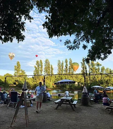 Terrasse du Snack des Pirates en bord de Dordogne avec montgolfières dans le ciel