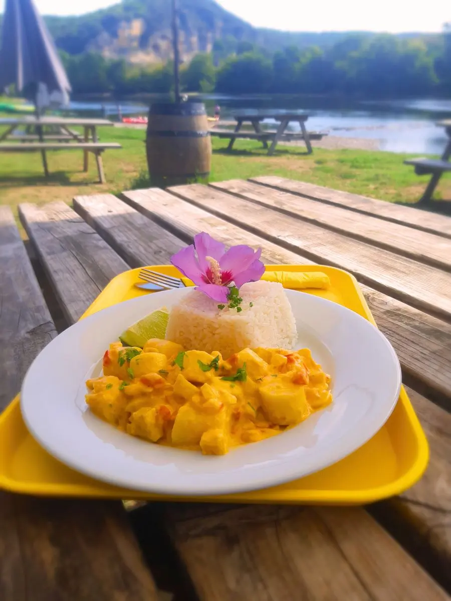 Moqueca de poisson brésilienne servie en terrasse, avec vue sur la Dordogne à La Roque-Gageac.